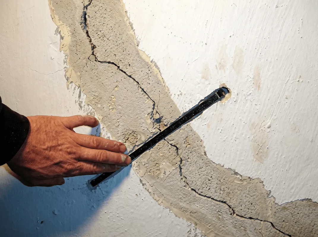 A wall with a large crack is being inspected by a professional in Knoxville, TN